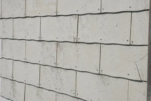 Graue rechteckige Fassadenplatten, horizontal überlappend und mit Nägeln befestigt.