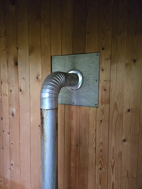 Flache Platte an einer Leitungsdurchführung durch eine Wand.