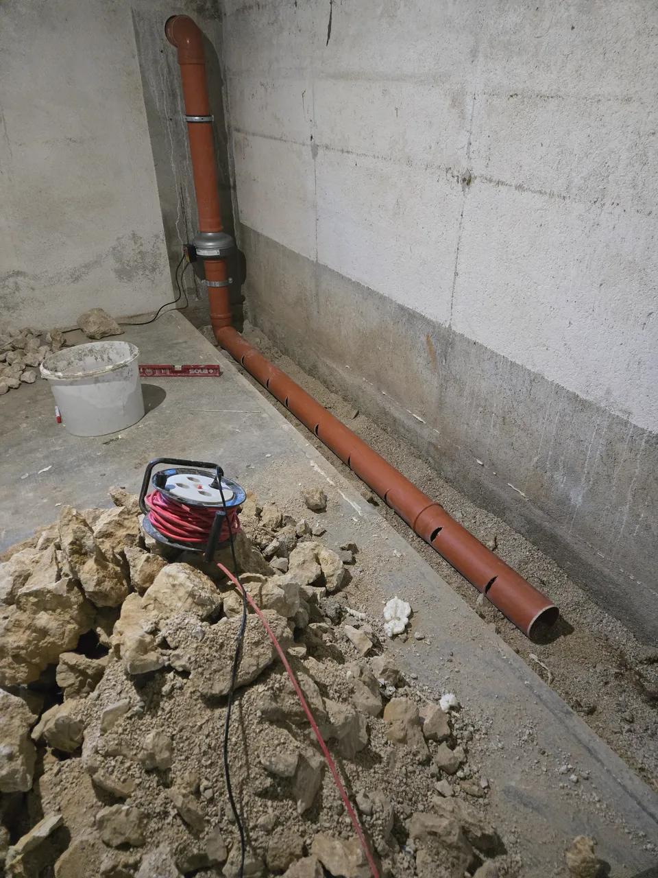Einbau einer Leitung unter der Bodenplatte während einer Radonsanierung.