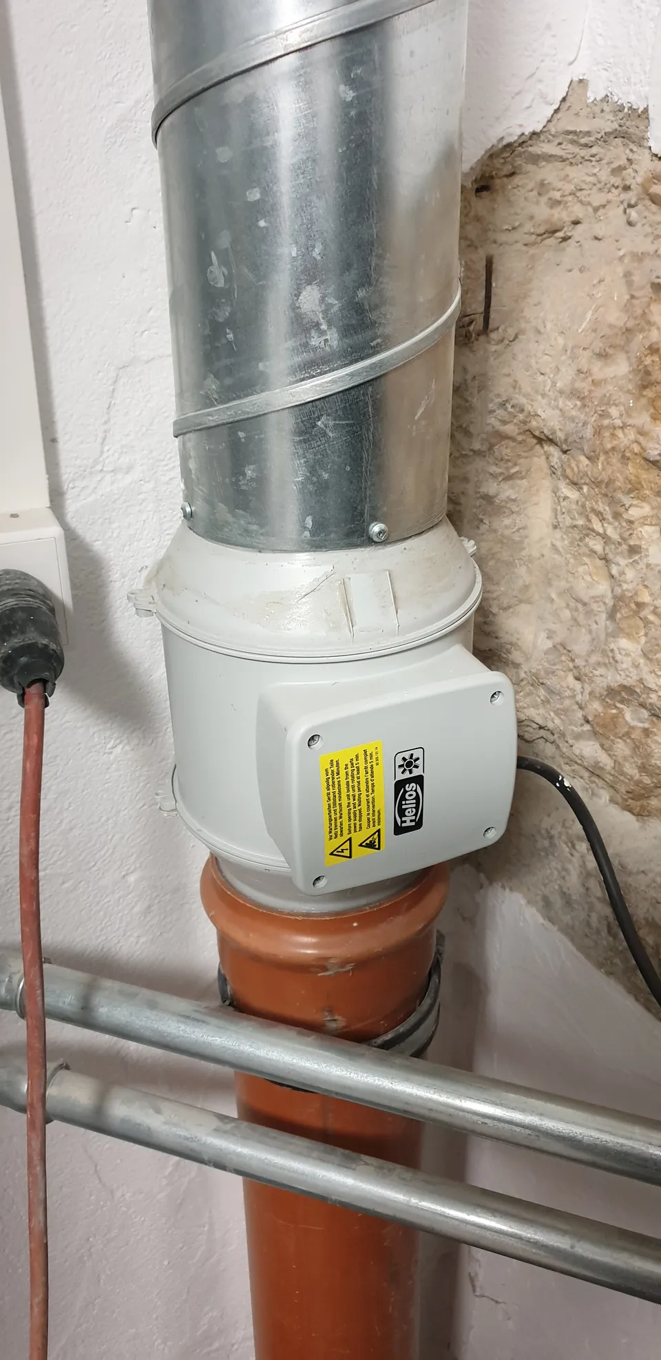 An einer Leitung montierter Ventilator in einem Technikraum.
